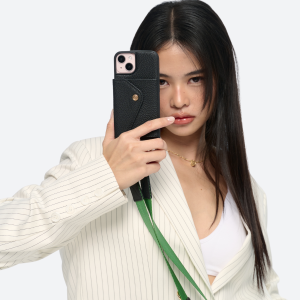 Model wearing the black Bandolier-style leather crossbody phone case, demonstrating its practicality with the adjustable strap comfortably slung over the shoulder.